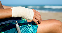 Man on a beach with a bandaged hand
